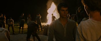 Movie still from “The Maze Runner” (2014), directed by Wes Ball – A man standing in front of a fire at night; Medium shot, Over the shoulder angle