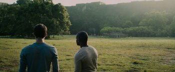 Movie still from “The Maze Runner” (2014), directed by Wes Ball – Two men are standing in a grassy field; Medium shot, Over the shoulder angle