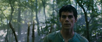 Movie still from “The Maze Runner” (2014), directed by Wes Ball – A young man standing in the middle of a forest; Close Up shot, Low angle
