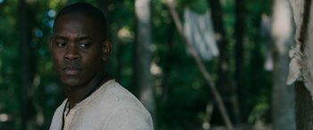 Movie still from “The Maze Runner” (2014), directed by Wes Ball – A man standing in the woods wearing a white shirt; Close Up shot, Over the shoulder angle