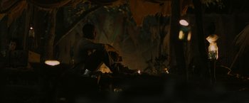 Movie still from “The Maze Runner” (2014), directed by Wes Ball – A man sitting on the ground near a fire pit; Wide shot, Low angle