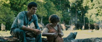 Movie still from “The Maze Runner” (2014), directed by Wes Ball – Two young people sitting on a log in the woods; Medium shot, Low angle