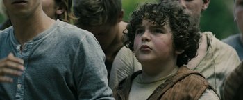 Movie still from “The Maze Runner” (2014), directed by Wes Ball – A boy with curly hair is looking at the camera while another boy looks on; Close Up shot, Over the shoulder angle