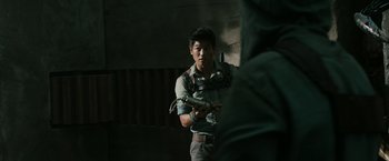 Movie still from “The Maze Runner” (2014), directed by Wes Ball – A man holding something in his hand while standing next to a wall; Medium shot, Over the shoulder angle
