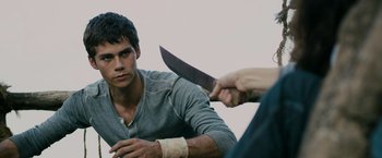 Movie still from “The Maze Runner” (2014), directed by Wes Ball – A man holding a knife in front of another man's face; Medium shot, Over the shoulder angle