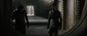 Movie still from “The Maze Runner” (2014), directed by Wes Ball – A man holding a gun while standing next to another man; Medium shot, Low angle