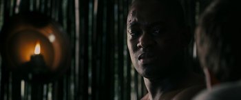 Movie still from “The Maze Runner” (2014), directed by Wes Ball – A man's face in front of a bamboo forest; Close Up shot, Over the shoulder angle