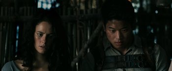 Movie still from “The Maze Runner” (2014), directed by Wes Ball – A man and a woman standing next to each other in front of a wooden fence; Close Up shot, Low angle