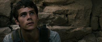 Movie still from “The Maze Runner” (2014), directed by Wes Ball – A man with a backpack looking up at a brick wall; Close Up shot, Over the shoulder angle
