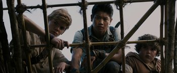 Movie still from “The Maze Runner” (2014), directed by Wes Ball – Two young men sitting on top of a wooden structure; Medium shot, Low angle
