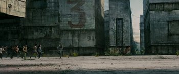 Movie still from “The Maze Runner” (2014), directed by Wes Ball – A man walking on a dirt road next to a building; Extreme Wide shot, High angle