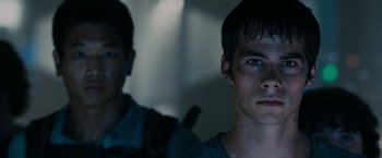 Movie still from “The Maze Runner” (2014), directed by Wes Ball – A man with a gun in his hand and another man with a gun in his other hand; Close Up shot, Low angle