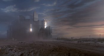 Movie still from “The Meaning of Life” (1983), directed by Terry Jones – Two people are standing on a dirt road near a building; Extreme Wide shot, Low angle