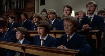 Movie still from “The Meaning of Life” (1983), directed by Terry Jones – A group of young men sitting in rows in a church; Medium shot, High angle