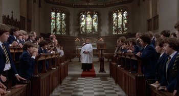 Movie still from “The Meaning of Life” (1983), directed by Terry Jones – A priest standing in front of a group of people; Wide shot, Low angle