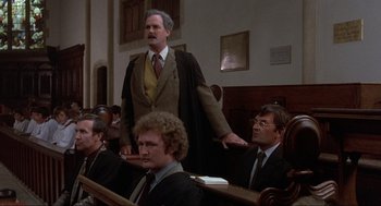 Movie still from “The Meaning of Life” (1983), directed by Terry Jones – A group of men in suits sitting in a courtroom; Medium shot, Low angle