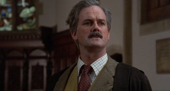 Movie still from “The Meaning of Life” (1983), directed by Terry Jones – An older man with a mustache wearing a suit and tie; Close Up shot, Low angle
