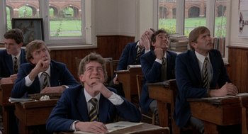 Movie still from “The Meaning of Life” (1983), directed by Terry Jones – A group of men sitting at a desk in a classroom; Medium shot, Low angle