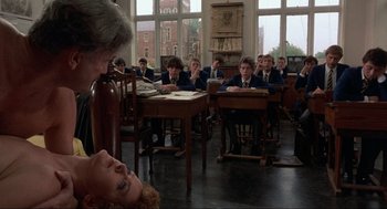 Movie still from “The Meaning of Life” (1983), directed by Terry Jones – A group of people sitting in front of a classroom; Medium shot, Over the shoulder angle