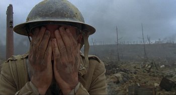 Movie still from “The Meaning of Life” (1983), directed by Terry Jones – A man in a helmet covering his face with his hands; Close Up shot, Low angle