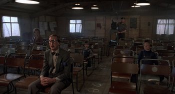 Movie still from “The Meaning of Life” (1983), directed by Terry Jones – A group of people sitting in a room with chairs; Wide shot, Over the shoulder angle