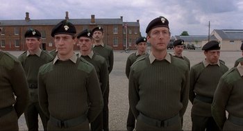 Movie still from “The Meaning of Life” (1983), directed by Terry Jones – A group of men standing next to each other in uniform; Medium shot, Low angle