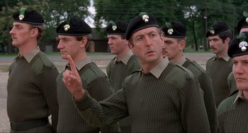 Movie still from “The Meaning of Life” (1983), directed by Terry Jones – A group of men in military fatigues are standing in a line; Medium shot, Low angle