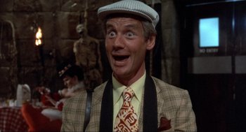 Movie still from “The Meaning of Life” (1983), directed by Terry Jones – A person wearing a suit and tie; Close Up shot, High angle