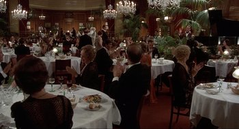 Movie still from “The Meaning of Life” (1983), directed by Terry Jones – A group of people sitting at tables in a restaurant; Wide shot, High angle