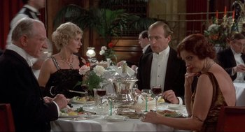 Movie still from “The Meaning of Life” (1983), directed by Terry Jones – A group of people sitting at a table with wine glasses; Medium shot, High angle