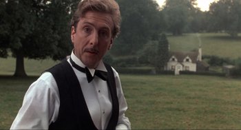Movie still from “The Meaning of Life” (1983), directed by Terry Jones – A man wearing a vest and bow tie in a field; Medium shot, Low angle