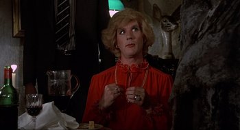 Movie still from “The Meaning of Life” (1983), directed by Terry Jones – A woman in a red dress is holding a necklace; Close Up shot, Over the shoulder angle