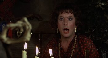 Movie still from “The Meaning of Life” (1983), directed by Terry Jones – A woman in a red and black dress with candles; Close Up shot, Over the shoulder angle