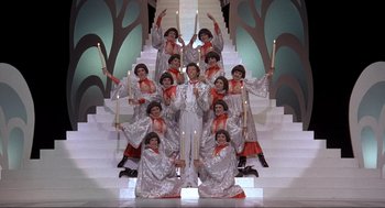 Movie still from “The Meaning of Life” (1983), directed by Terry Jones – A group of people standing on top of steps holding candles; Wide shot, Low angle