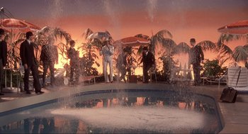 Movie still from “The Meaning of Life” (1983), directed by Terry Jones – A group of people standing under an open umbrella; Extreme Wide shot, Low angle