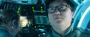 Movie still from “The Meg” (2018), directed by Jon Turteltaub – A man with glasses is sitting in a helicopter cockpit; Close Up shot, Low angle