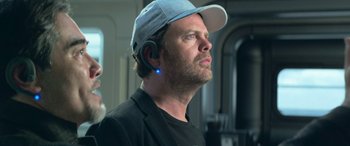 Movie still from “The Meg” (2018), directed by Jon Turteltaub – A man wearing a baseball cap and ear buds; Close Up shot, Over the shoulder angle
