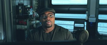 Movie still from “The Meg” (2018), directed by Jon Turteltaub – A man wearing glasses and a hat is sitting in front of a computer; Close Up shot, Low angle