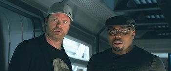 Movie still from “The Meg” (2018), directed by Jon Turteltaub – Two men standing next to each other in a room; Close Up shot, Low angle