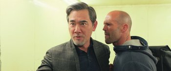 Movie still from “The Meg” (2018), directed by Jon Turteltaub – A man in a suit and a man in a black shirt; Medium shot, Over the shoulder angle