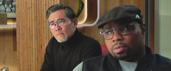 Movie still from “The Meg” (2018), directed by Jon Turteltaub – A man and a man wearing glasses sitting next to each other; Close Up shot, Over the shoulder angle