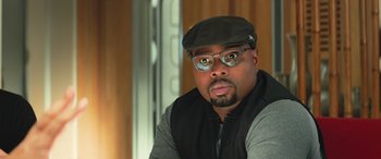 Movie still from “The Meg” (2018), directed by Jon Turteltaub – A person wearing glasses and a hat; Close Up shot, Over the shoulder angle