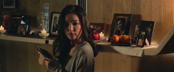 Movie still from “The Meg” (2018), directed by Jon Turteltaub – A woman sitting in front of a wall with pictures on the wall; Medium shot, Over the shoulder angle