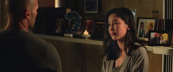 Movie still from “The Meg” (2018), directed by Jon Turteltaub – A woman sitting in front of a fireplace in a living room; Close Up shot, Over the shoulder angle