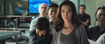 Movie still from “The Meg” (2018), directed by Jon Turteltaub – A group of people that are standing in front of a tv; Medium shot, Over the shoulder angle