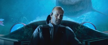 Movie still from “The Meg” (2018), directed by Jon Turteltaub – A bald man with a goatee is sitting in a car; Close Up shot, Low angle