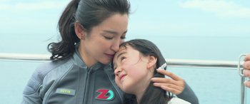 Movie still from “The Meg” (2018), directed by Jon Turteltaub – A woman and a girl are kissing each other's cheek; Close Up shot, Over the shoulder angle