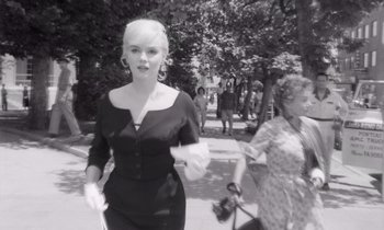 Movie still from “The Misfits” (1961), directed by John Huston – A woman walking down the street in a black dress; Medium shot, Low angle