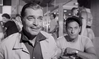 Movie still from “The Misfits” (1961), directed by John Huston – A black - and - white photo of two men sitting next to each other; Medium shot, Over the shoulder angle