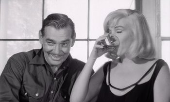 Movie still from “The Misfits” (1961), directed by John Huston – A man and a woman are drinking a drink together; Close Up shot, High angle
